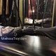 Mistress Troy makes adjustments to Her leather body bag